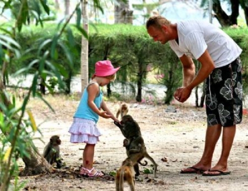 A dad and his little daughter playing with monkeys